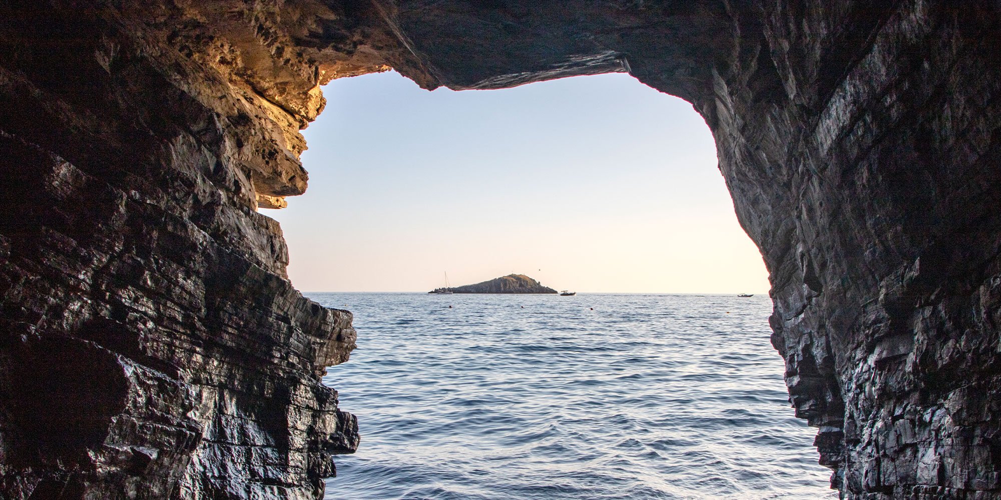 Looking out from inside cave towards ocean and small island piece of land in the distance