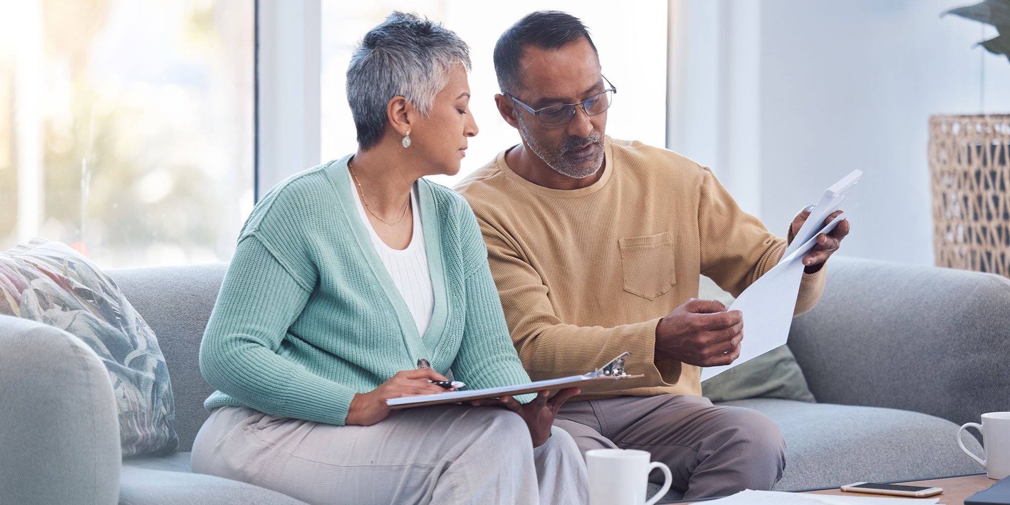 Finance, documents and senior couple on sofa with bills