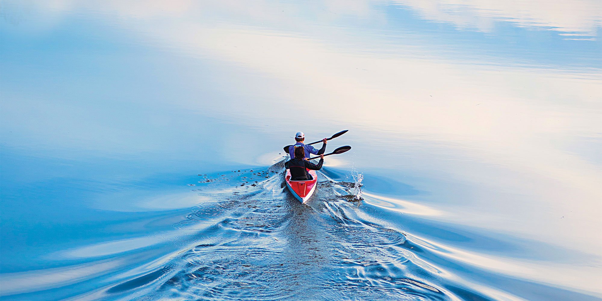 reflection of two people in canoe kayak on still water