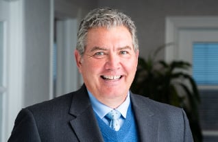 Headshot of Commerce Trust's Chris Hamm wearing a navy suit jacket over a blue sweater and tie